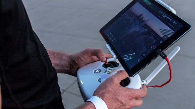 A person operating a UAV using a handheld remote controller and screen