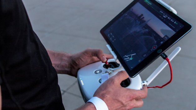 A person operating a UAV using a handheld remote controller and screen