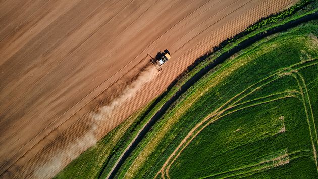 A drone shot of a machine on a dry patch of land