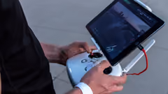 A person operating a UAV using a handheld remote controller and screen